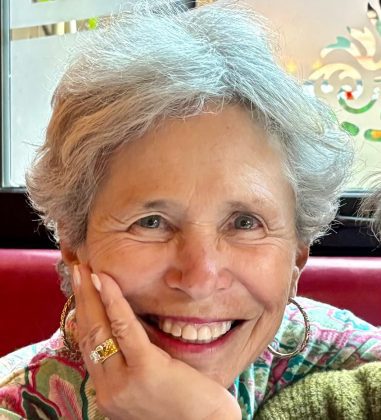 Headshot of Elaine Gantz Berman, smiling with her chin resting on her hand, wearing a colorful patterned top.